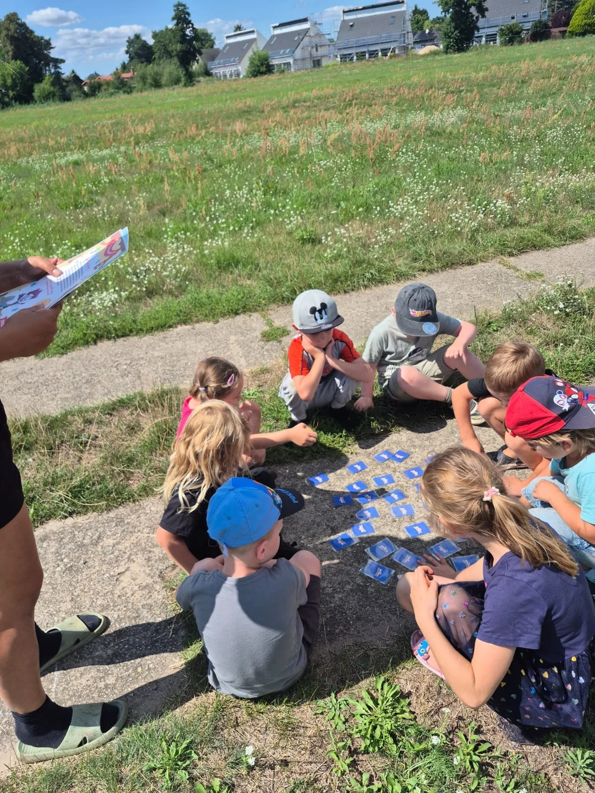 Kinder sitzen mit einer Karte auf der Wiese